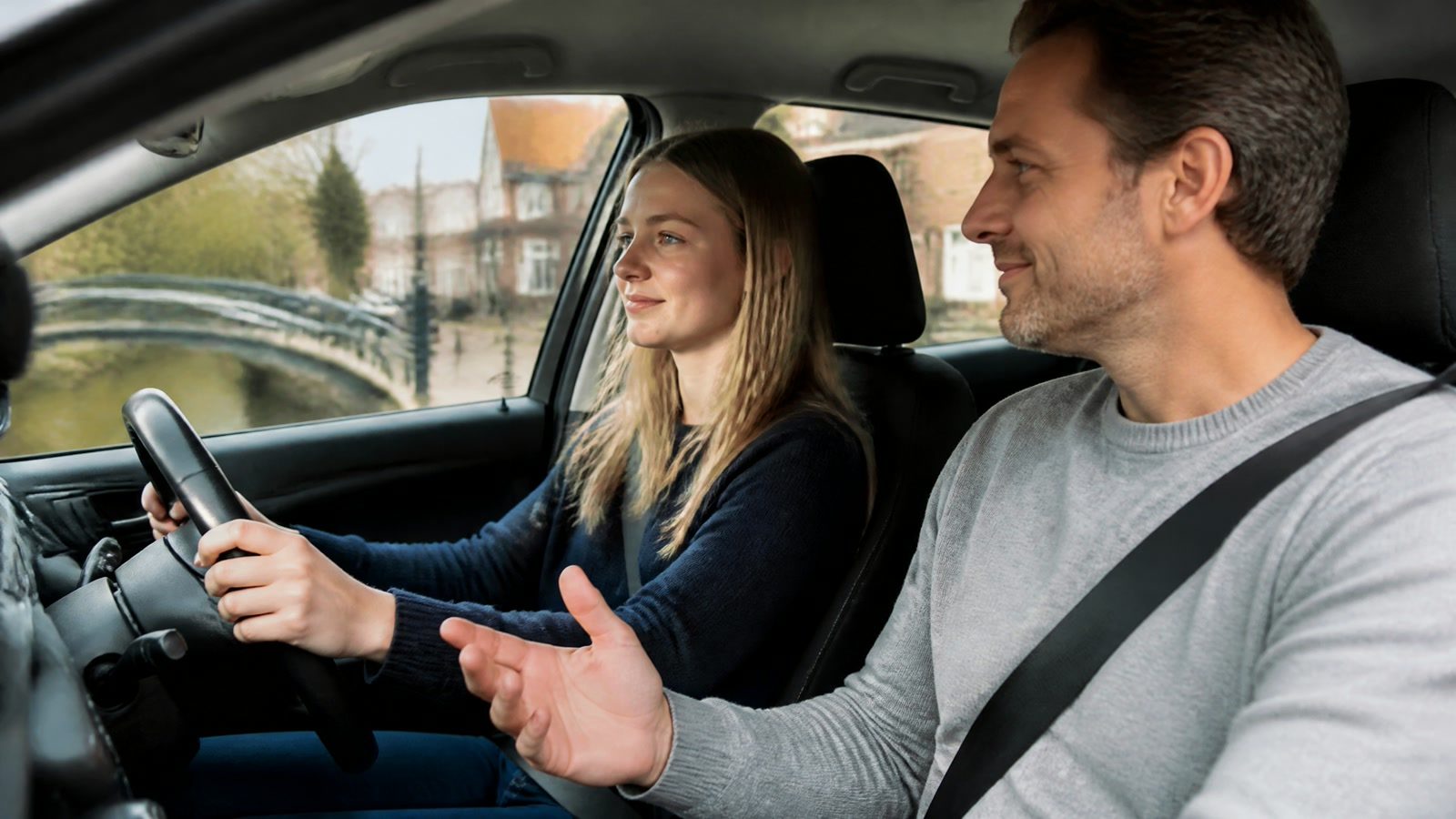 Een instructeur geeft uitleg aan een leerling achter het stuur in een auto